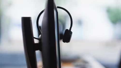 Empty Call Center Office with Headsets Resting on Computer Monitors Closeup