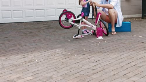 Girl and man work on pink bicycle outdoors