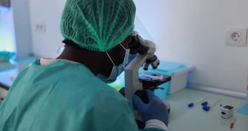 African Medical Worker in Hazmat Suit Working with Micoroscope Inside Laboratory Hospital
