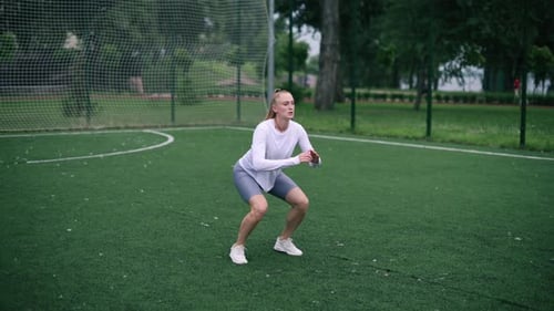 Woman Doing Squats on Green Sports Field