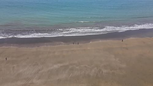 Drone aerial shot hovering over the beach as tourists walk by in the distance, Bahia Ballena, Costa