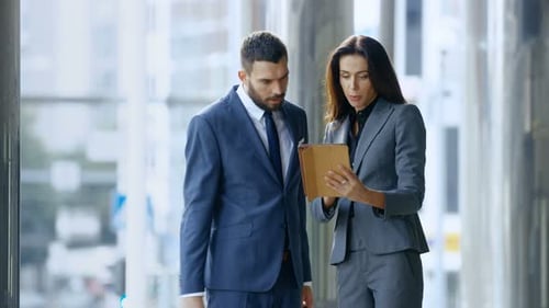 Professionals Discussing Data on Tablet Inside Office Building