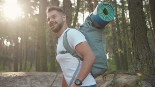 Close Up of the Handsome Young Man Hiker Standing in the Forest Turning His Head and Smiling at