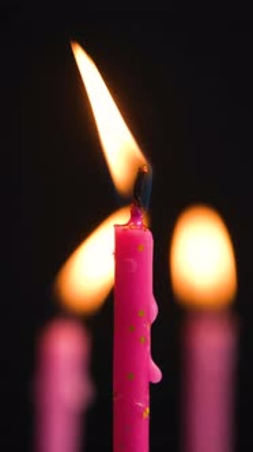 Three Cake Candles Burning on a Black Background