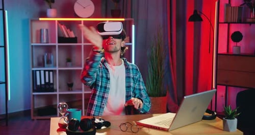 Close up of attractive man which working on imaginary screen in augmented reality goggles in home