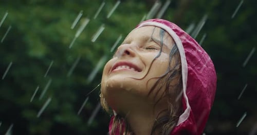 Portrait of Happy Girl in Raincoat Enjoying Rain