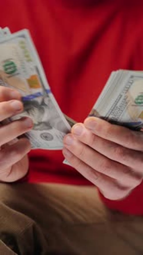 Person Counting Stack of One Hundred Dollar Bills