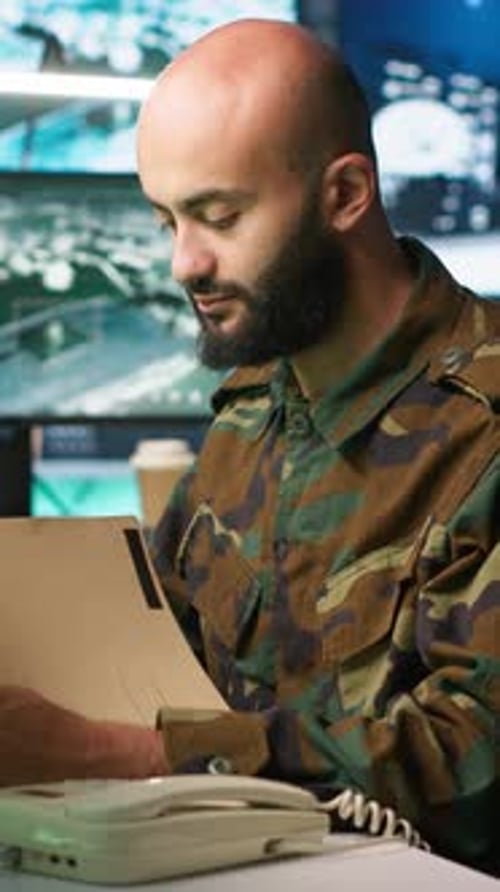 Man in Camouflage Answers Phone at Desk