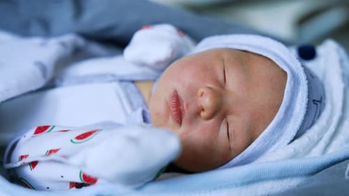 Angelic newborn baby in little cap lies on his back. Cute child sleeping peacefully. Close up.