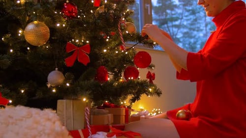 Woman Decorating Christmas Tree with Ornaments and Gifts