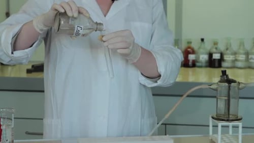 Person Pours Chemical Into Test Tube in Lab