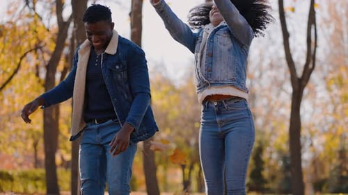 Black Woman with Man Plays with Leaves Throwing Up and Down