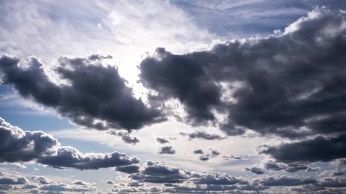 Zeitraffer von Cumuluswolken, die sich am blauen Himmel gegen die Sonne bewegen