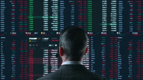 Der Trader arbeitet mit mehreren Computerbildschirmen voller Charts und Datenanalysen und einem Börsenmakler