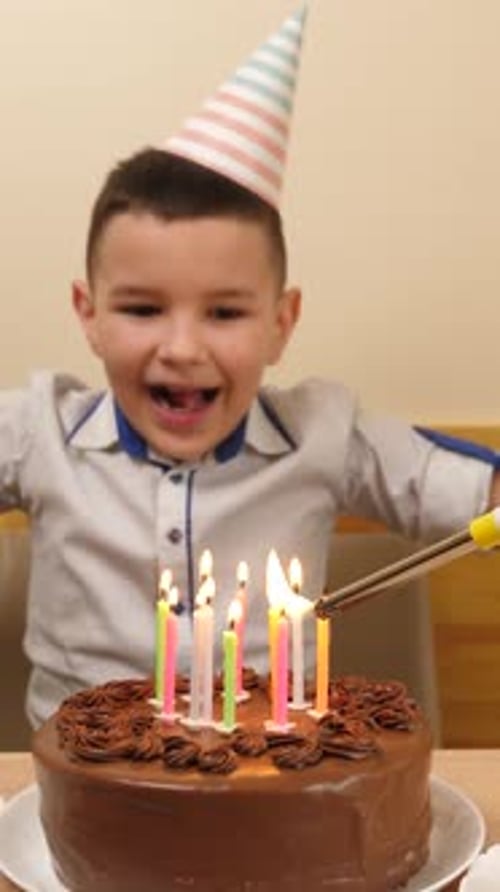 39. The boy sits in front of a table with a festive cake and candles, blows them out and receives gi