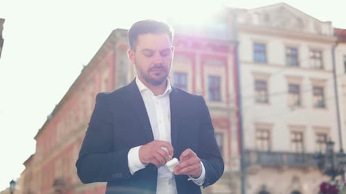 Close Up of Caucasian Bearded Businessman Standing on Street and Talking Headphones From the Holder