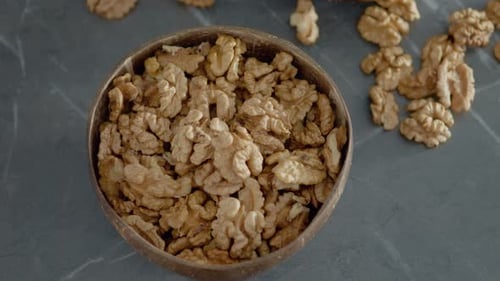 Bowl of Shelled Walnuts on Grey Marble Surface