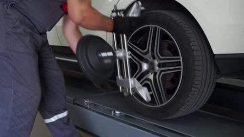 Auto Technician Aligns Car Wheel with Precision Equipment in Garage Vehicle Maintenance Auto Service