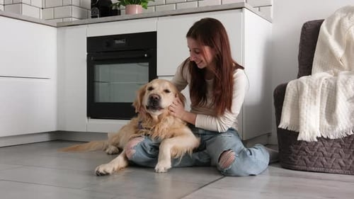 Woman P petting her golden retriever dog in kitchen