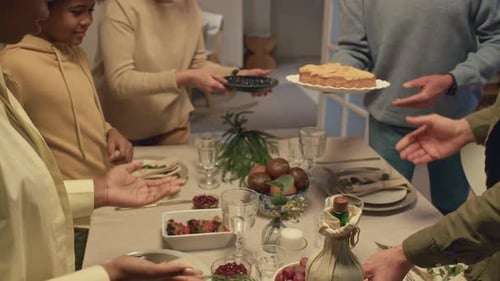 Family and Friends Place Dishes on Dining Table