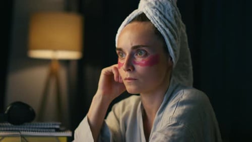 Woman with towel and eye patches on face