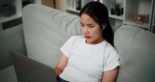 Woman Using Laptop on Couch at Home