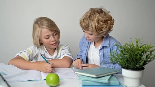 Ensino Fundamental Primário, Meninos e Meninas, Irmãos, Estudando na Mesa Escrevendo em Livro e Tablet