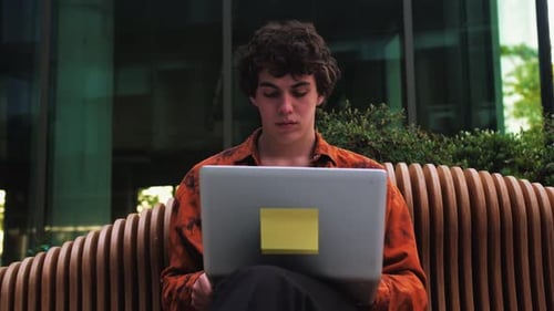 Besorgter, müder Profi erledigt die Arbeit am Laptop, schließt den Computerdeckel, sitzt draußen in der Nähe von Modern