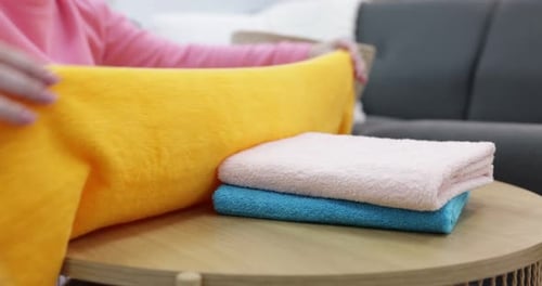 Woman Folding Colorful Towels in a Bright Home