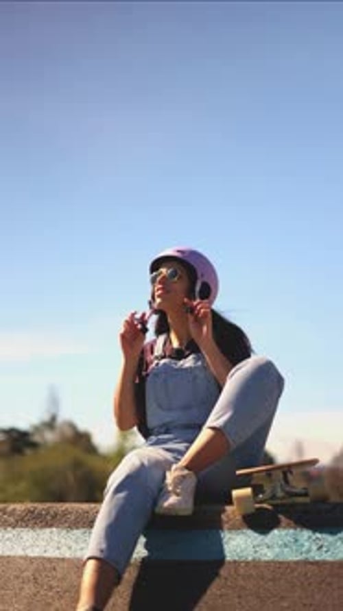 Woman Wearing Helmet Sitting with Skateboard Outdoors