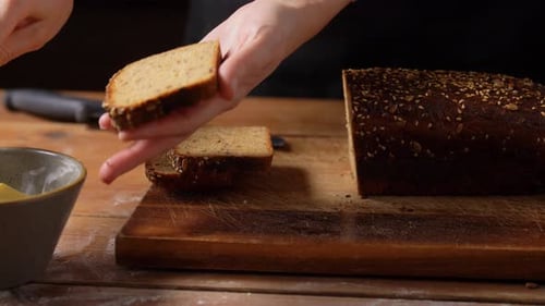Butter being spread on sliced whole grain bread
