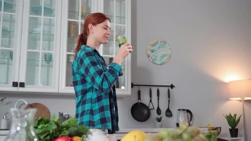 Woman Drinking Green Smoothie in Kitchen
