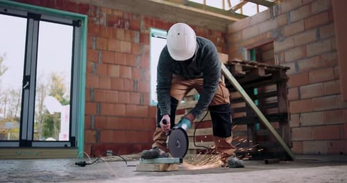 Worker using angle grinder, sparks flying from metal cutting, indoor construction site, focused on