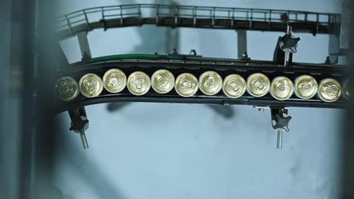 Golden cans seen from above moving through a production line in a factory