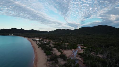 ascending drone shot over horseshoe bay beach in Magnetic Island at sunset with clouds in the sky, Q