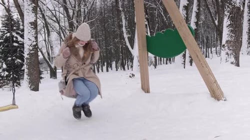 Woman Swinging on a Swing Set in Winter
