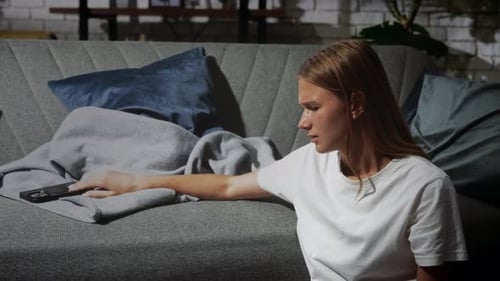Sad Woman Sitting Next to Couch in Apartment