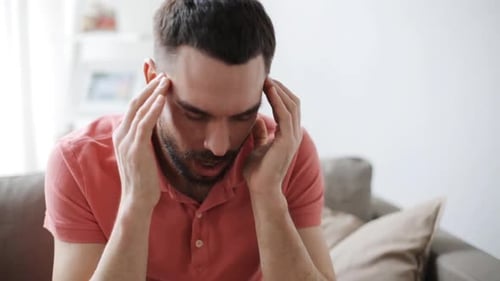 Adult Man Massaging Temples Sitting on Couch