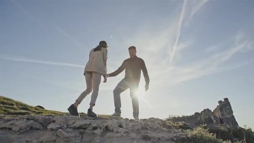 A Couple of Happy Tourists Jumping From Joy to the Top of the Mountain Against the Background of the