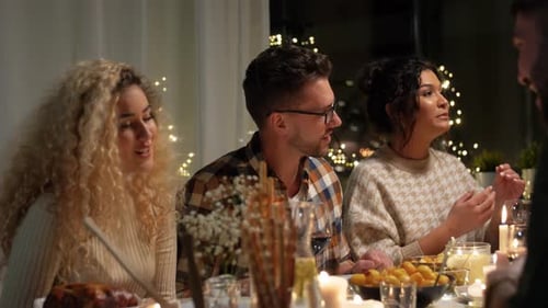 Group of Friends Talking Around Dinner Table at Night