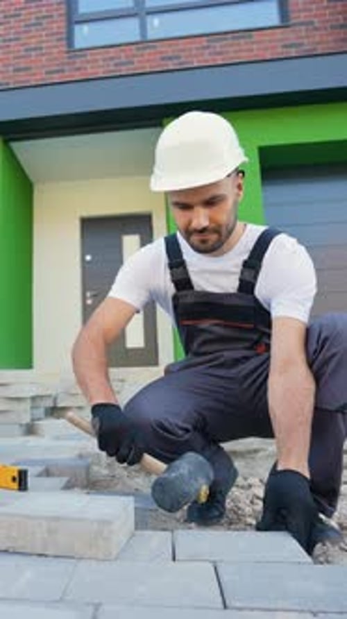 Construction Worker Laying Brick Pavers on Driveway