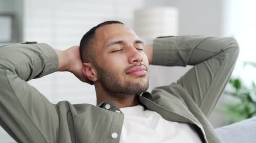Man Relaxing, Arms Behind Head, in Bright Living Room
