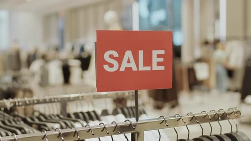 Red Sale Sign on Rack in Clothing Store
