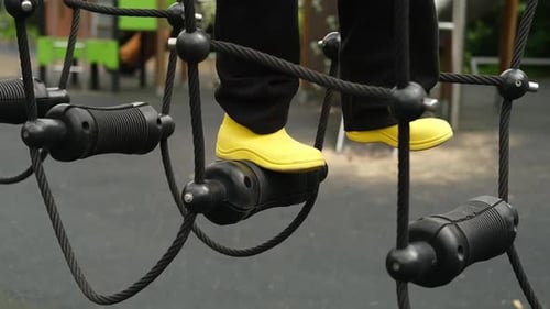 A Child Boy is Stepping Up an Alpine Grid in a Park on a Playground on a Hot Summer Day Kids