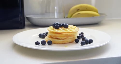 Delicious Waffles with Blueberries and Syrup in Kitchen