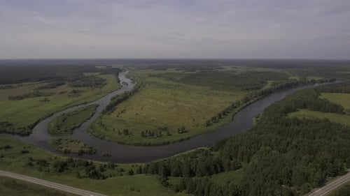 Aerial View of a Bending River Flowing and Crossing Wide Green Field Stock Footage Summer Rural