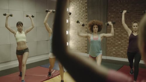 Group of adult women exercising with weights in gym