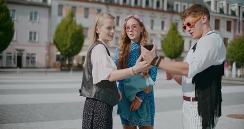 Man Sharing Smart Phone with Female Friends in Town
