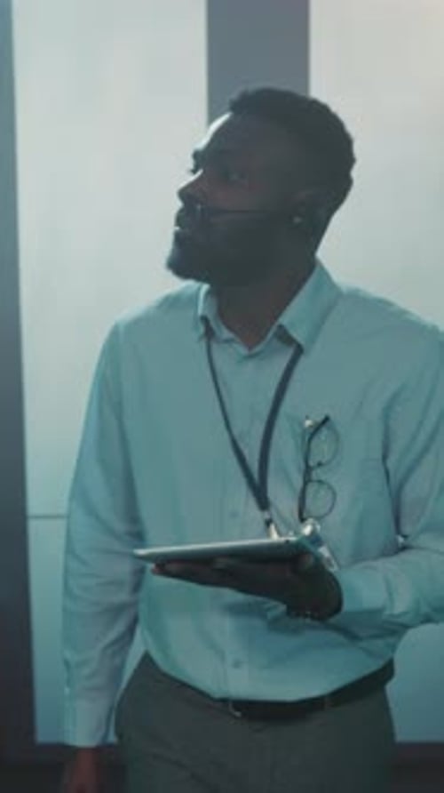Man with Tablet in Server Room Inspecting Data