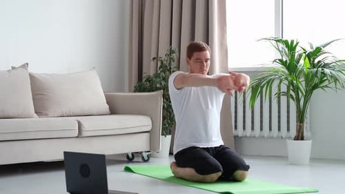 Man Stretches Wrists Before Yoga at Home